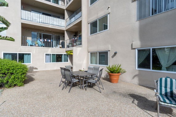 View of an apartment building from a patio area with outdoor furniture.