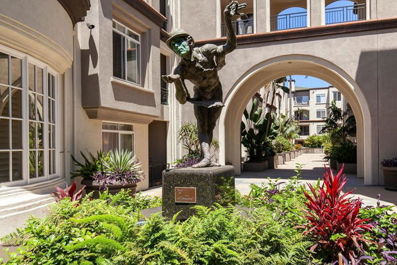 Front view of an apartment building with an archway and a statue in the courtyard.