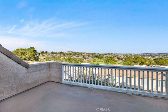 Rooftop view with railing overlooking residential area and landscape.