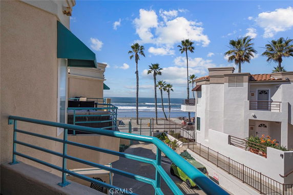 View of seaside buildings with palm trees and ocean in the background.