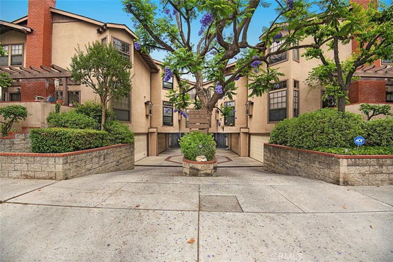 Front view of a multi-story residential building with garages and a tree in front.