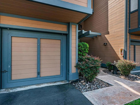 Front view of a building entrance with a garage door and pathway.