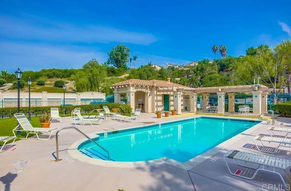 Outdoor swimming pool with sun loungers and a small building nearby.