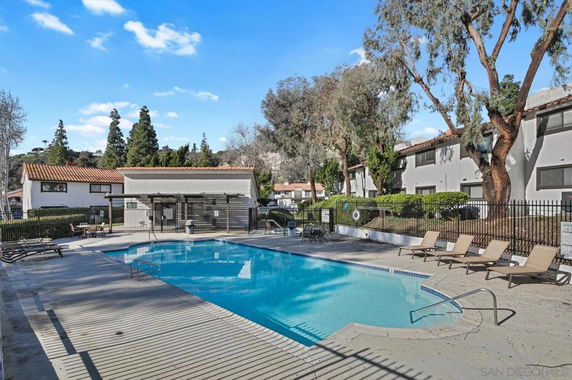 Outdoor swimming pool area with lounge chairs and surrounding buildings.
