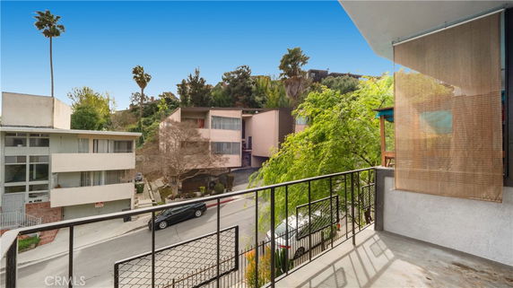 View from a balcony showing nearby residential buildings and a street.