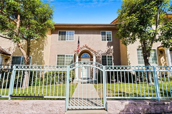 Front view of a two-story house with a wrought iron fence and American flag.
