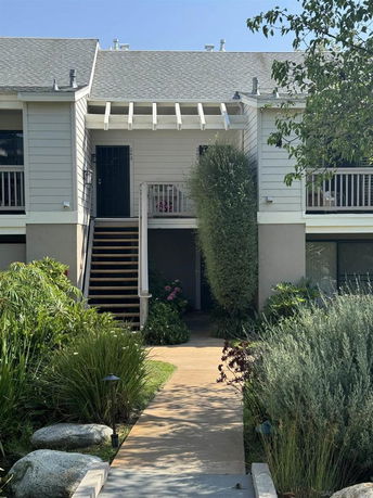 Front view of a two-story house with a staircase leading to the entrance.