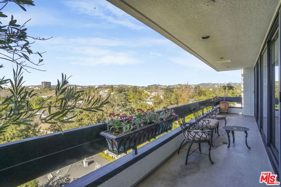 Balcony view showing a wide scenic overlook of surrounding areas with trees and distant buildings.