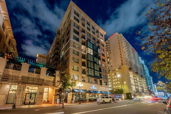Front view of a multi-story building with commercial spaces on the ground floor, seen at night.