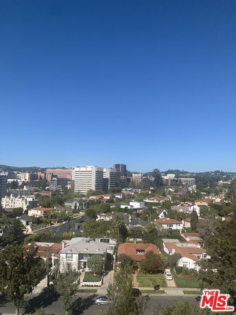 Panoramic view of a cityscape with residential and commercial buildings under a clear blue sky.