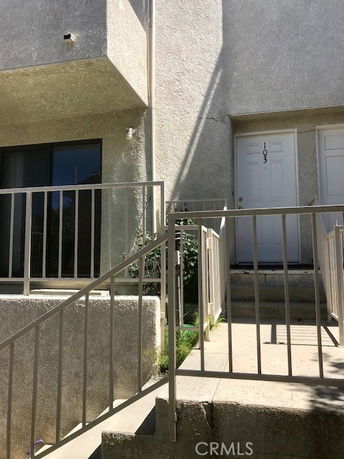 Front view of a two-story building with a staircase leading to a door labeled 103.