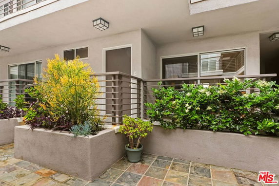 Front view of a modern apartment balcony with potted plants.