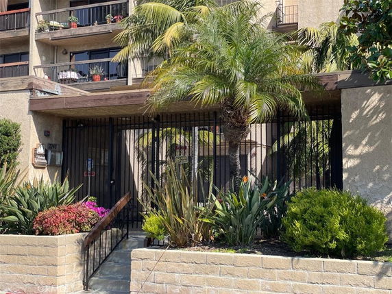 Front view of a multi-story building with balconies and iron gate.