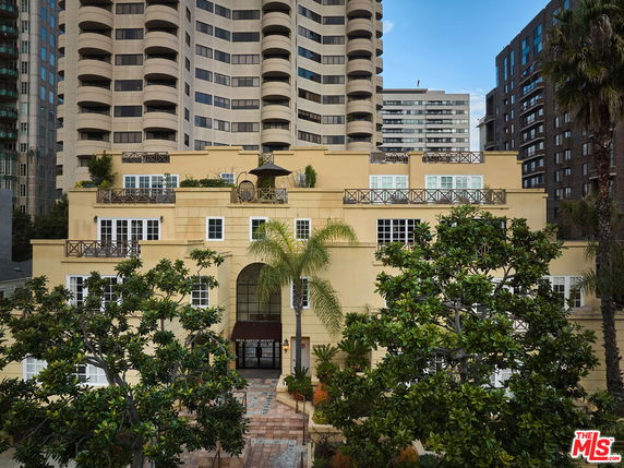 Front view of a multi-story building with balconies and large windows.