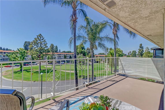 Balcony view showing surrounding residential area with palm trees and green lawns.