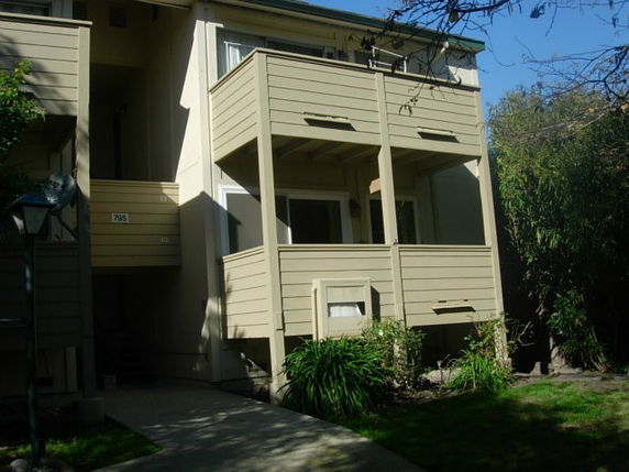 Front view of a multi-story building with two small balconies.