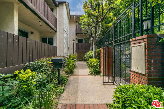 Front view of a two-story residential building with a walkway and gated entrance.