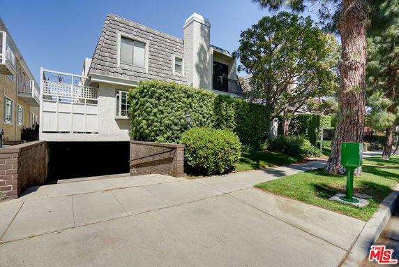 Front view of a two-story house with a sloped roof and a garage entry.