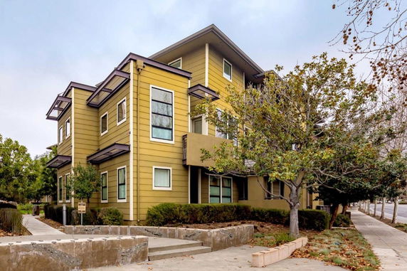 Front view of a multi-story house with modern architecture and green siding.
