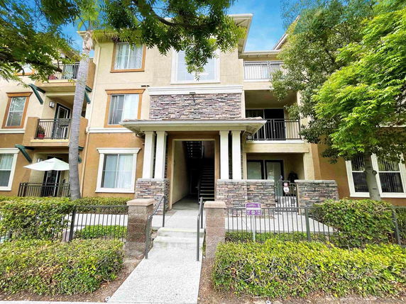 Front view of a multi-story residential building with balconies and stone accents.