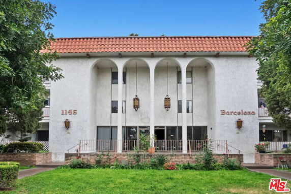 Front view of a multi-story building with arch design and red-tiled roof.