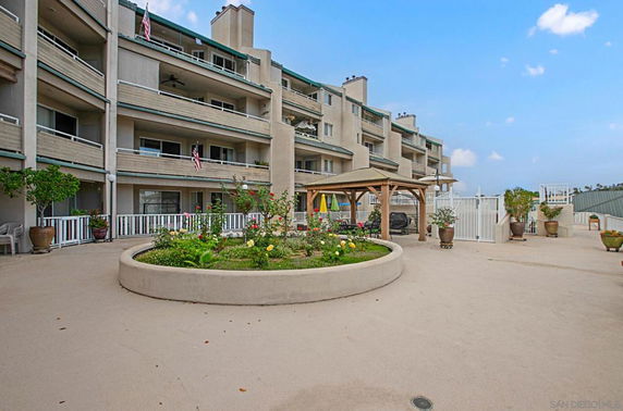 Front view of a multi-story apartment building with balconies and planters.