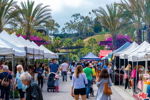 Outdoor market scene with tents and people walking.