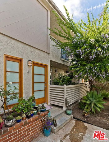 Front view of a two-story house with a small garden and potted plants.