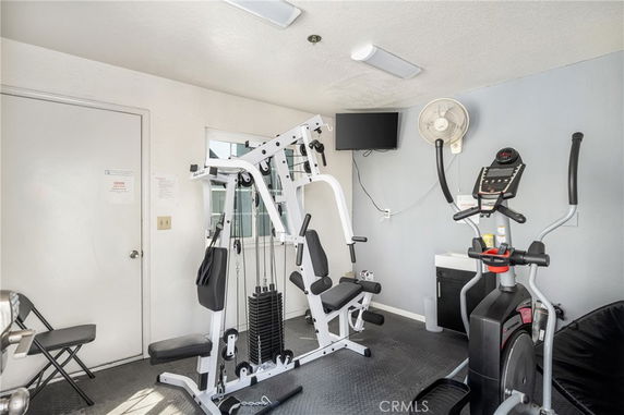 Interior of a gym room with exercise equipment including a weight machine and an elliptical trainer.