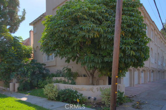 Front view of a multi-story residential building with garage entrances and lush greenery.