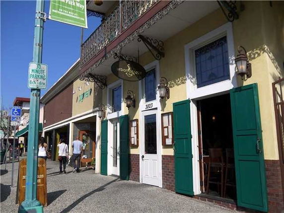 Front view of a two-story building with green shutters and balcony.