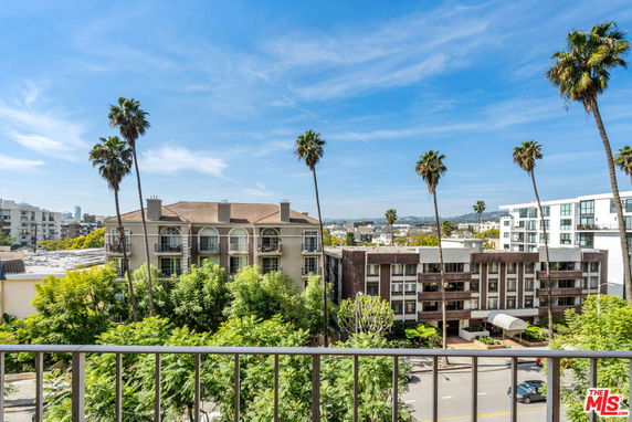 Panoramic view from a building overlooking surrounding buildings and palm trees.