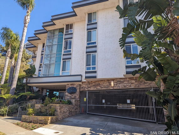 Front view of a multi-story building with a stone facade and gated entrance.