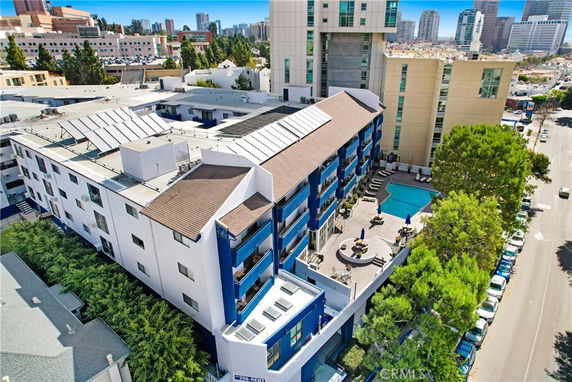 Aerial view of a multi-story building with a central courtyard and a swimming pool.