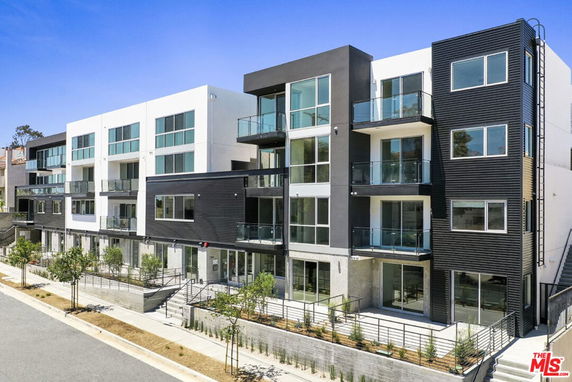 Front view of a modern multi-story apartment building with glass balconies.