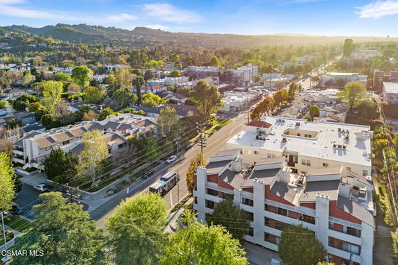Aerial view of residential and commercial buildings with surrounding greenery and roads.