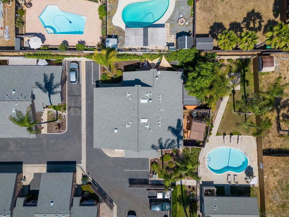 Aerial view of buildings with visible rooftops, including parking areas and swimming pools.
