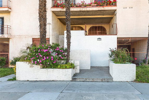 Front view of a residential building with balconies and entrance pathway.