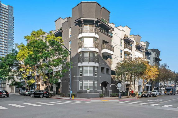 Front view of a modern multi-story residential building on a street corner.