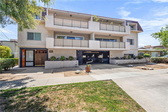 Front view of a multi-story apartment building with balconies and parking area.