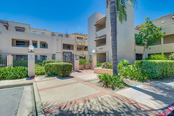 Front view of a multi-story apartment building with gated entrance.
