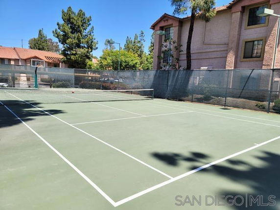 Tennis court with nets and surrounding residential buildings.