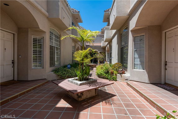 Courtyard view of a residential building with tiled floors and potted plants.