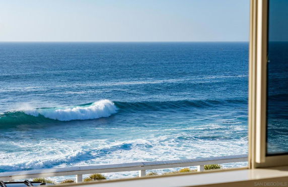 Panoramic view of the ocean with waves, seen through a window.