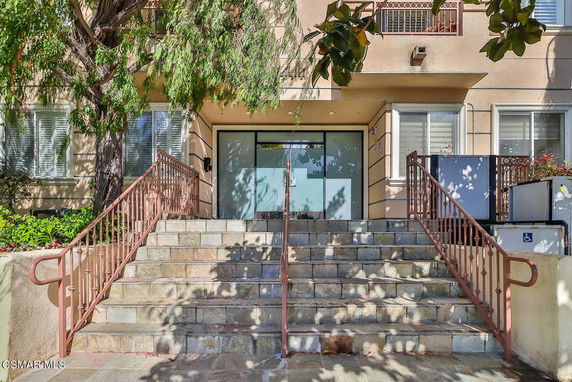 Front view of a residential building entrance with stairs and metal railings.