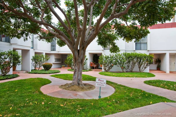 Courtyard view of a multi-story residential building with landscaped paths and trees.