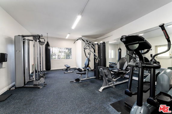 Room with various gym equipment including elliptical machines and weight racks.