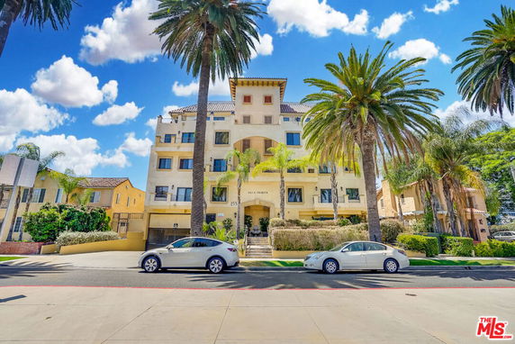 Front view of a multi-story residential building with palm trees in front.