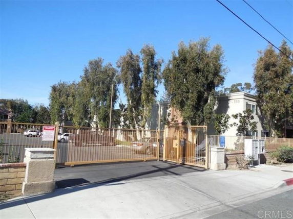 Front view of a gated residential building with surrounding trees.