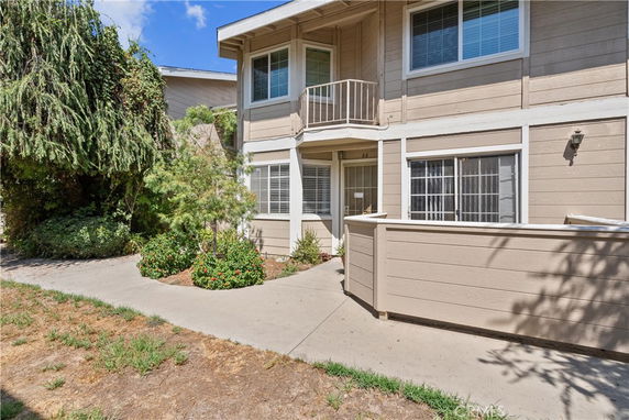 Front view of a two-story residential building with a small balcony and fenced entrance.